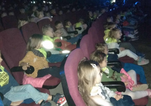 Dzieci siedzą w fotelach na widowni w kinie Luna czekając na rozpoczęcie przedstawienia